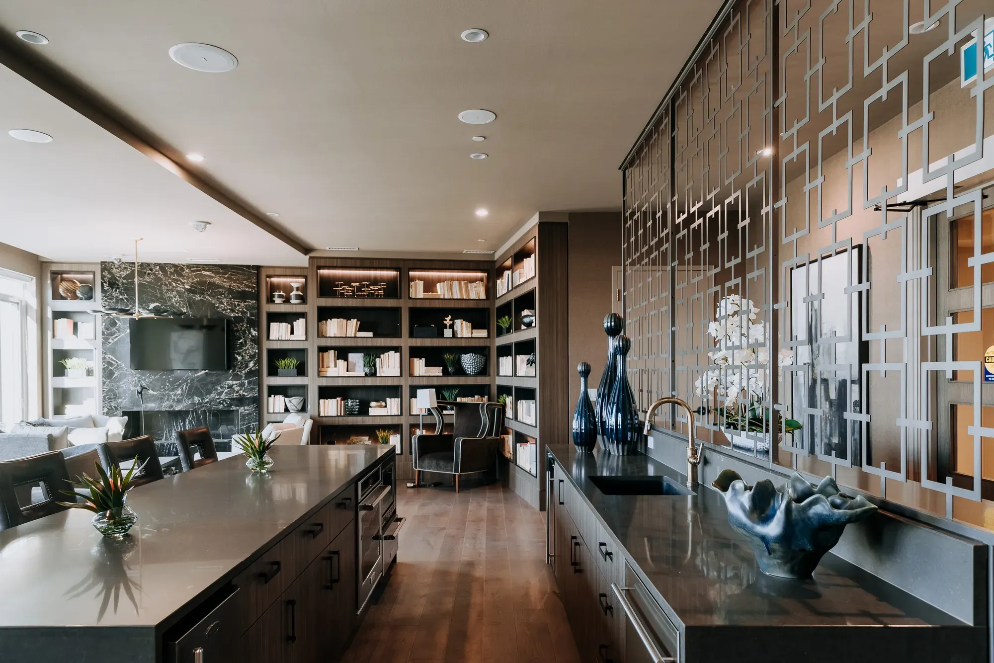 Modern kitchen and living area with a large island and dark elegant finishes.