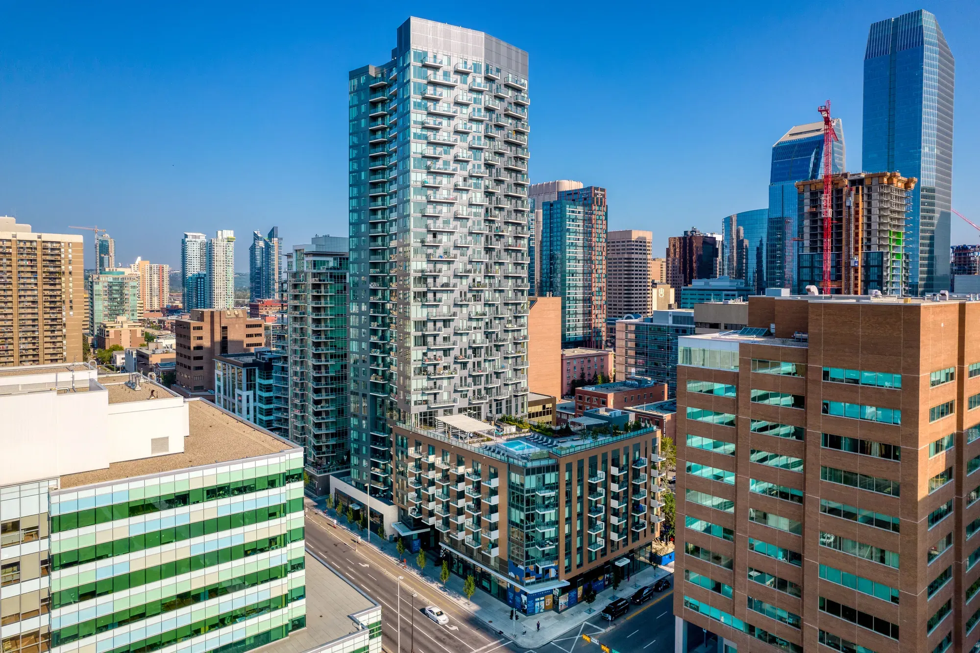 Modern tall building with many balconies dominates a sunny city skyline.