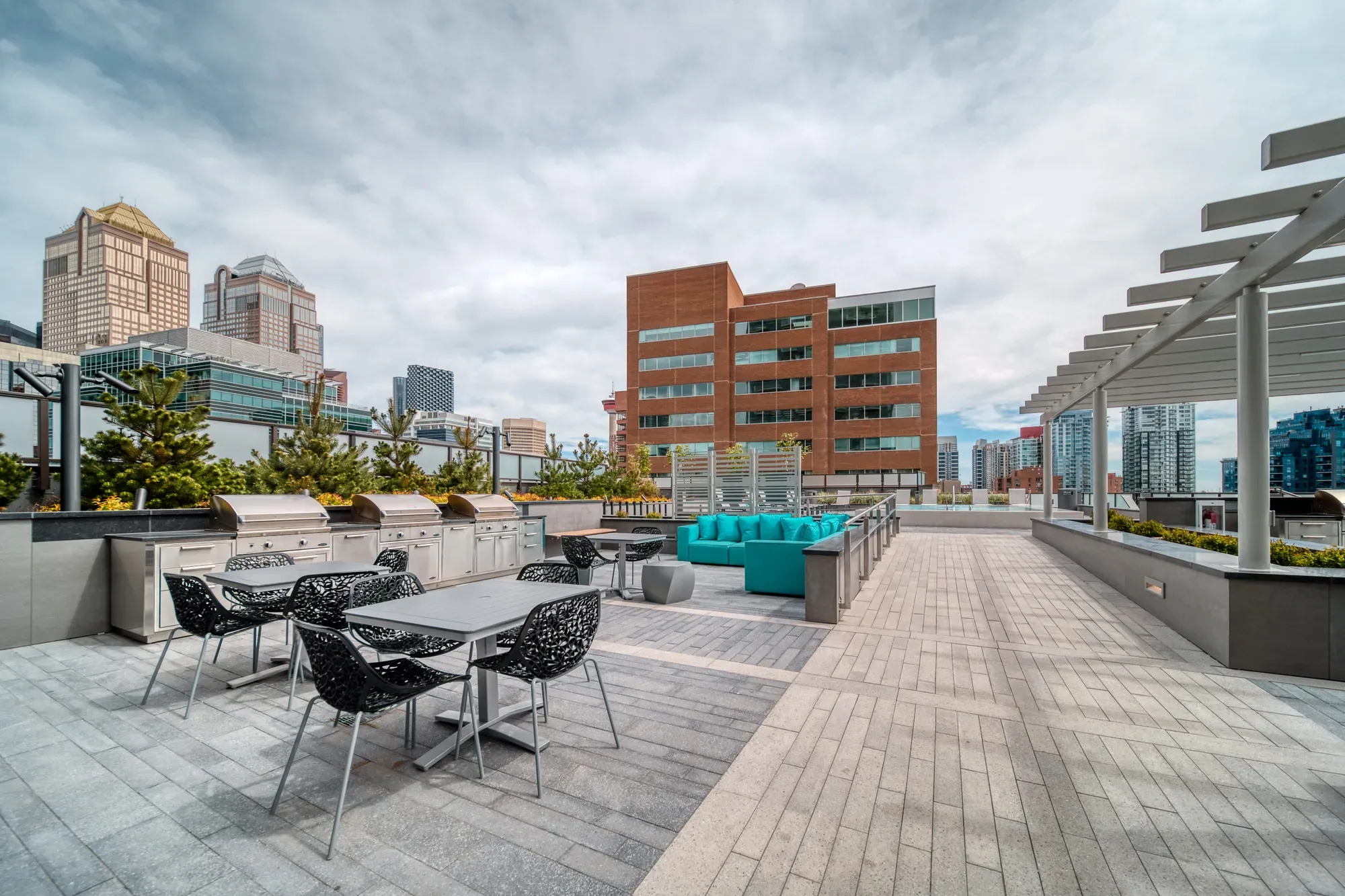 Modern rooftop patio with outdoor seating, grilling stations, and city skyline views.